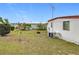 Exterior backyard of home featuring green grass, blue skies, and white siding at 1312 Apache Cir, Tavares, FL 32778