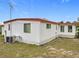 Exterior view of home with white siding, a red roof, and a well-maintained yard at 1312 Apache Cir, Tavares, FL 32778