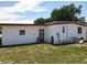 Exterior view of white mobile home with red trim, showing yard, door, and window at 1312 Apache Cir, Tavares, FL 32778