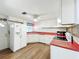 Bright kitchen featuring white cabinets, red countertops with playful decor and tile backsplashes at 1312 Apache Cir, Tavares, FL 32778