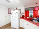 Bright kitchen features white cabinets, red accents, and modern appliances with a window view at 1312 Apache Cir, Tavares, FL 32778