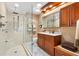 Bathroom with custom tiled shower, glass enclosure, and single sink vanity with custom wood cabinets at 1502 Aalto Pl, Lady Lake, FL 32159