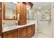 Elegant bathroom featuring double sinks, custom cabinetry, and a glass-enclosed shower at 1502 Aalto Pl, The Villages, FL 32159