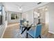 Bright dining room featuring wood flooring, large windows, an elegant table, and an adjacent kitchen area at 16721 Se 77Th Northridge Ct, The Villages, FL 32162