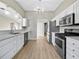 Well-lit kitchen features stainless steel appliances, white cabinetry, hardwood floors and modern countertops at 16721 Se 77Th Northridge Ct, The Villages, FL 32162