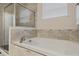 Bright bathroom showcasing a large bathtub with tiled surround and a glass-enclosed shower for a spa-like experience at 17024 Goldcrest Loop, Clermont, FL 34714