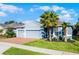 Charming single-story home with a well-manicured lawn, brick driveway, and beautiful palm trees at 17024 Goldcrest Loop, Clermont, FL 34714