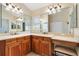 Bathroom featuring a dual sink vanity with wooden cabinets and large mirrors at 1797 Pamplico Ct, The Villages, FL 32162