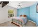 Bright bedroom featuring a window, ceiling fan, and blue accent wall at 1797 Pamplico Ct, The Villages, FL 32162