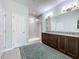 Bright bathroom with double sink vanity, framed mirror, granite countertop, and walk-in shower at 203 Silver Maple Rd, Groveland, FL 34736