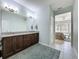 Bathroom leading to main bedroom features dark cabinets, neutral granite, and a large mirror at 203 Silver Maple Rd, Groveland, FL 34736