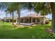 Manicured backyard featuring a patio, well-kept lawn, palm trees, and screened lanai at 2068 Darlington Dr, The Villages, FL 32162