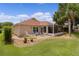 Backyard with patio, landscaping, and a screened lanai overlooking the green lawn at 2068 Darlington Dr, The Villages, FL 32162