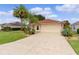 Front exterior featuring a well-manicured lawn, a two-car garage, and mature landscaping at 2068 Darlington Dr, The Villages, FL 32162