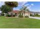 Inviting front yard with lush green lawn, mature palm trees, and colorful flower beds at 2068 Darlington Dr, The Villages, FL 32162