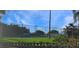 Tennis court behind a fence, surrounded by green landscaping and a blue sky at 20751 Queen Alexandra Dr, Leesburg, FL 34748