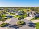 Picturesque aerial view of a neighborhood, showcasing well-maintained homes, green spaces, and a circular street design at 27023 Old English Ct, Leesburg, FL 34748