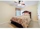 Comfortable bedroom featuring a floral-patterned bedspread, soft lighting, and a ceiling fan for added comfort at 27023 Old English Ct, Leesburg, FL 34748