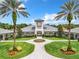 Elegant clubhouse featuring manicured landscaping, a circular driveway, and a clock tower under a cloudy blue sky at 27023 Old English Ct, Leesburg, FL 34748