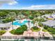 Aerial view of a resort-style pool with lush landscaping and a clubhouse on a sunny day at 27023 Old English Ct, Leesburg, FL 34748