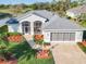 Charming home with a gray roof, screen porch, two car garage, and manicured landscaping at 27023 Old English Ct, Leesburg, FL 34748