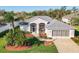 An inviting home featuring a well-manicured lawn, mature palms, and an attached two-car garage at 27023 Old English Ct, Leesburg, FL 34748