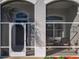 Close-up of the screened front entry featuring a decorative glass door and comfortable seating area with striped chairs at 27023 Old English Ct, Leesburg, FL 34748