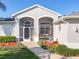 Close-up of the screened front entry with arched windows, beautiful landscaping, and a decorative water feature at 27023 Old English Ct, Leesburg, FL 34748