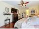 Bright main bedroom with ceiling fan, decorative wall art, hard wood floors, and a comfortable queen bed at 27023 Old English Ct, Leesburg, FL 34748