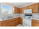 Kitchen featuring a double sink, wood cabinets, and white appliances at 2712 Benavides Dr, The Villages, FL 32162