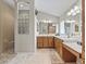 Bright bathroom with a double vanity, large mirror, and tiled shower with glass block window at 3156 Vandenberg Ct, The Villages, FL 32163