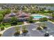 Aerial view of the community clubhouse and pool featuring a large parking area and meticulously kept grounds at 3156 Vandenberg Ct, The Villages, FL 32163