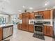 Open kitchen with stainless steel appliances, wood cabinetry, and adjacent dining area, filled with natural light at 3156 Vandenberg Ct, The Villages, FL 32163