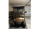 Tan Yamaha Golf Cart with brown striped seats in a garage ready to play golf at 3183 Hatch Ln, The Villages, FL 32162