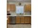 Kitchen featuring light wood cabinets, a stainless steel dishwasher, and tile flooring at 3183 Hatch Ln, The Villages, FL 32162