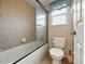 Bathroom featuring a combined shower and tub with glass doors, a toilet, and a window with natural light at 3234 Cypress Grove Dr, Eustis, FL 32736