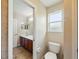 Half bathroom with tile floors, toilet, single sink with a brown cabinet, and a vanity mirror at 3234 Cypress Grove Dr, Eustis, FL 32736