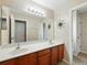 Bathroom featuring double sinks with wood cabinets, a large mirror, and stylish sun decor at 3234 Cypress Grove Dr, Eustis, FL 32736