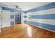 Bedroom with blue and white striped walls, a ceiling fan, wood floors, and a closet with shelves at 3234 Cypress Grove Dr, Eustis, FL 32736