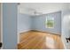 Bedroom with light blue walls, hardwood floors, a ceiling fan, and a window overlooking the backyard at 3234 Cypress Grove Dr, Eustis, FL 32736