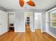 Bright bedroom featuring wood floors, ceiling fan, and closet with shelving for optimal storage at 3234 Cypress Grove Dr, Eustis, FL 32736