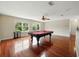 Game room with hardwood floors, billiard table, ceiling fan, and multiple windows overlooking lush greenery at 3234 Cypress Grove Dr, Eustis, FL 32736