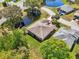 Aerial view of a home featuring lush landscaping, brick driveway, and a serene pond at 32800 Oak Park Dr, Leesburg, FL 34748