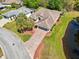 Aerial view of the house featuring brick driveway, beautiful landscaping, mature trees, and adjacent water feature at 32800 Oak Park Dr, Leesburg, FL 34748