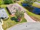 Aerial view of home featuring lush landscaping, brick driveway, and a serene pond at 32800 Oak Park Dr, Leesburg, FL 34748