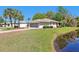 Single-story house overlooking pond features an attached two-car garage, lush lawn, and mature landscaping at 32800 Oak Park Dr, Leesburg, FL 34748