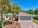 Charming home featuring an inviting entryway, two-car garage, mature trees, and beautiful landscaping at 32800 Oak Park Dr, Leesburg, FL 34748