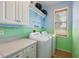 Charming laundry room with washer, dryer, upper cabinets, and cheerful blue and green decor at 32800 Oak Park Dr, Leesburg, FL 34748