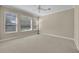 Bedroom with neutral carpet, ceiling fan, three windows, and light beige paint at 341 Silver Maple Rd, Groveland, FL 34736