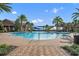 Beautiful community pool with blue and yellow shades, featuring plenty of lounge chairs and surrounding palm trees at 341 Silver Maple Rd, Groveland, FL 34736